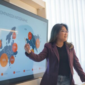 Asian woman presenting a business infographic on global market trends in an office setting.